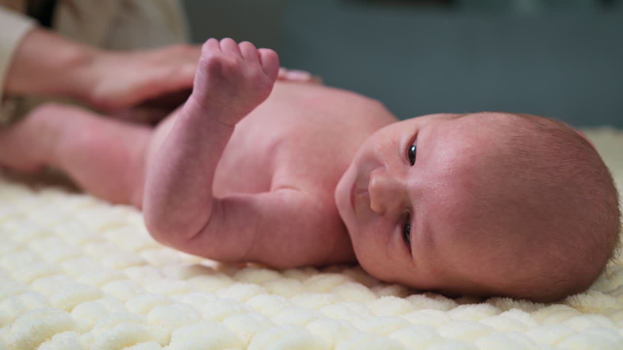 Nahaufnahme eines neugeborenen Babys, das auf einer weichen Decke liegt und dessen Hand sanft von den Eltern berührt wird