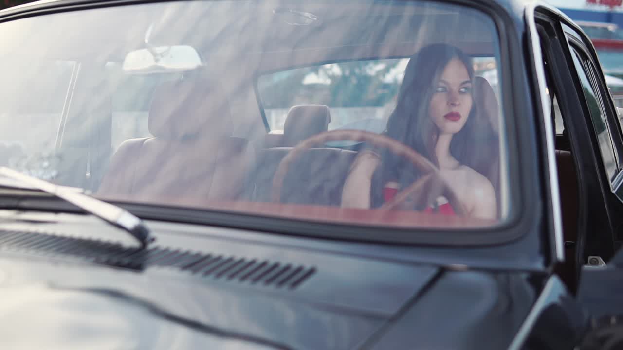 una mujer conduciendo un coche de época.