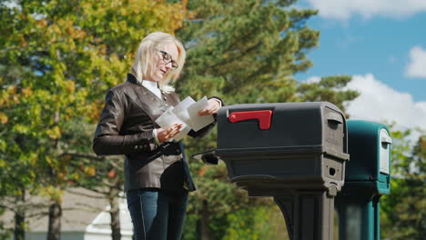 woman collects letters from mail box