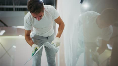 A Dedicated Worker Applying Finishing Touches to a Freshly Painted Wall, Demonstrating Skill and Attention to Detail in a Modern Workspace Setting