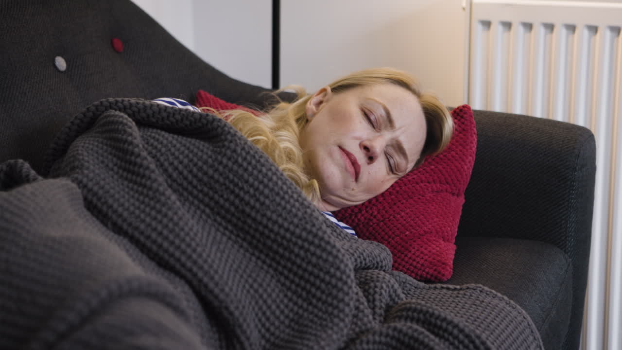 Woman sleeping on couch under blanket