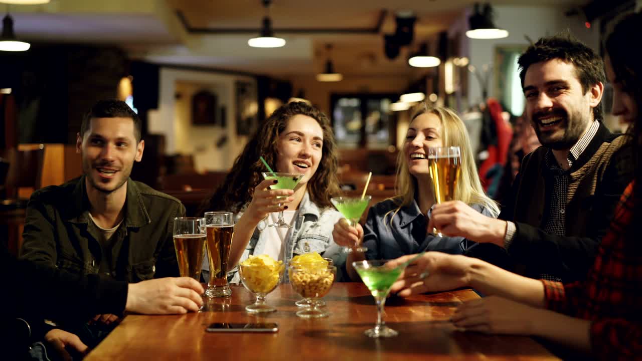 giovani di bell'aspetto si stanno divertendo, bevendo e socializzando in un bar elegante insieme. gli amici sono felici, si stanno godendo la serata in buona compagnia.