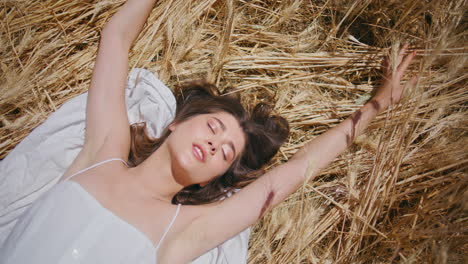 sensual woman enjoying sunshine laying in spikelets close up. girl playing hands