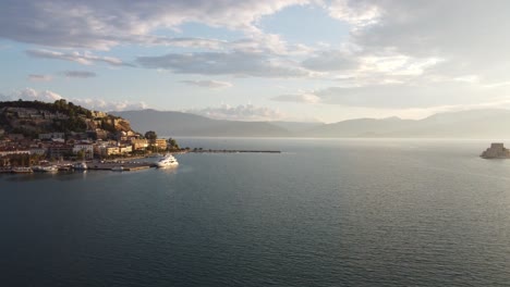 Vista-Aérea-De-La-Pintoresca-Ciudad-Mediterránea-De-Nauplio-En-La-Región-Del-Peloponeso-De-Grecia,-Durante-Una-Tarde-Nublada-Con-La-Fortaleza-Marina-De-Bourtzi-En-El-Lado-Derecho-Y-Yates-En-El-Puerto-|-4k