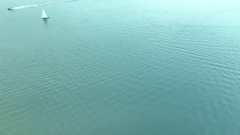 aerial view of a solitary sailboat on jeziorak lake in siemiany, poland, with gentle ripples on the water under a cloudy sky