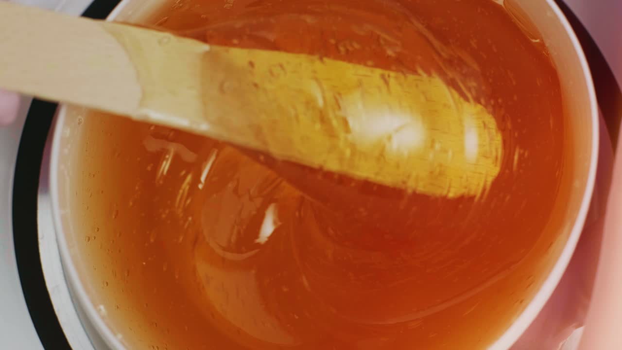 Liquid sugar for skin epilation. Close up shot. depilation and beauty concept - sugar paste or wax honey for hair removing with wooden waxing spatula sticks