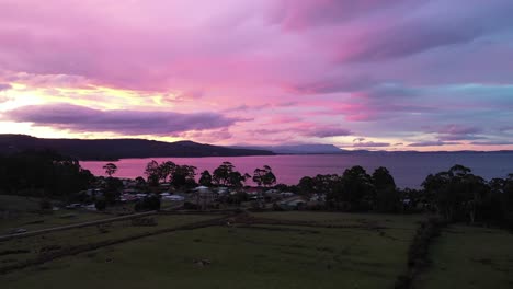 Impresionante-Puesta-De-Sol-Púrpura-Sobre-La-Playa-De-La-Isla,-Vista-Aérea-De-Drones-Alrededor-De-La-Bahía-Con-Un-Cielo-épico-Y-Una-Cordillera-Con-Una-Pequeña-Choza-Y-Un-Bosque