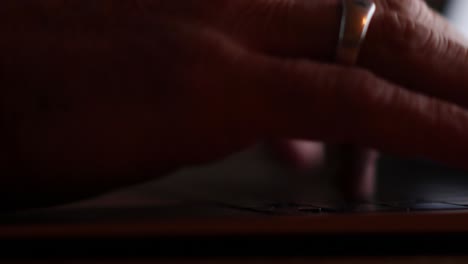 primer plano de las manos de un hombre escribiendo en una computadora portátil ligeramente iluminada por la pantalla
