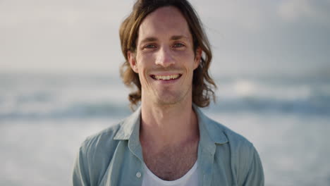 portrait of handsome young man smiling enjoying successful lifestyle on warm sunny beach seaside background