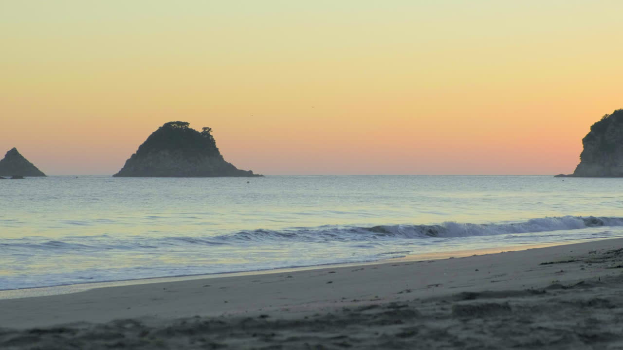 olas matutinas al amanecer en la playa de hahei, nueva zelanda