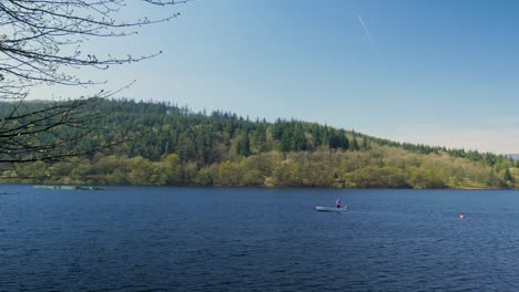 man fishing on a boat casting fishing pole in lady bower reservoir sunny day waves moving calm sailing in the peak district shot in 4k
