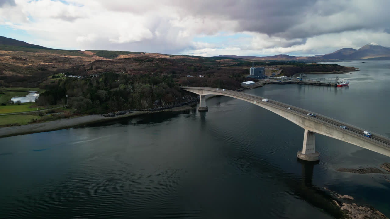 물 이 구름 과 다리 를 반영 하는 것 처럼 자동차 들 이 스코틀랜드 의 스카이 다리 를 지나간다