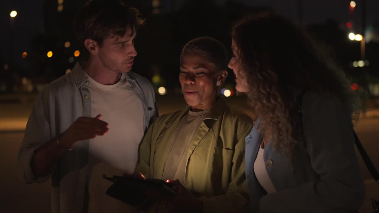 People looking at a tablet at night