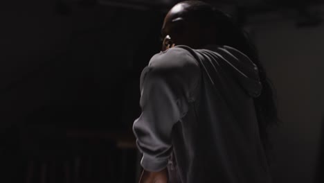 studio portrait shot of young woman wearing hoodie dancing with low key lighting against black background