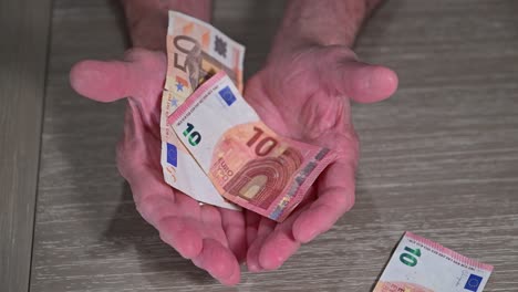 European-retirement-on-few-euros-as-senior-citizen-hands-are-outstretched-to-catch-income-for-European-pensioner-lifestyle