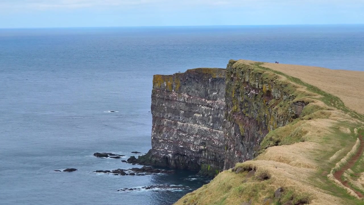 Vista panoramica delle spettacolari scogliere costiere a Kalfshamarsvik, sulla costa settentrionale di Skagafjordur, che si affacciano sull'Oceano Atlantico settentrionale sotto un cielo azzurro limpido in Islanda.