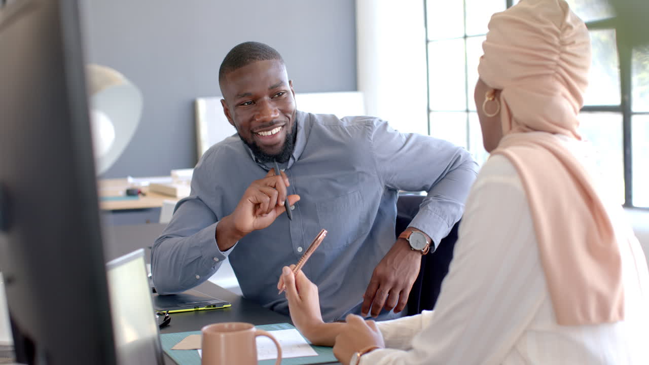 Smiling businessman discussing work with colleague in modern office setting