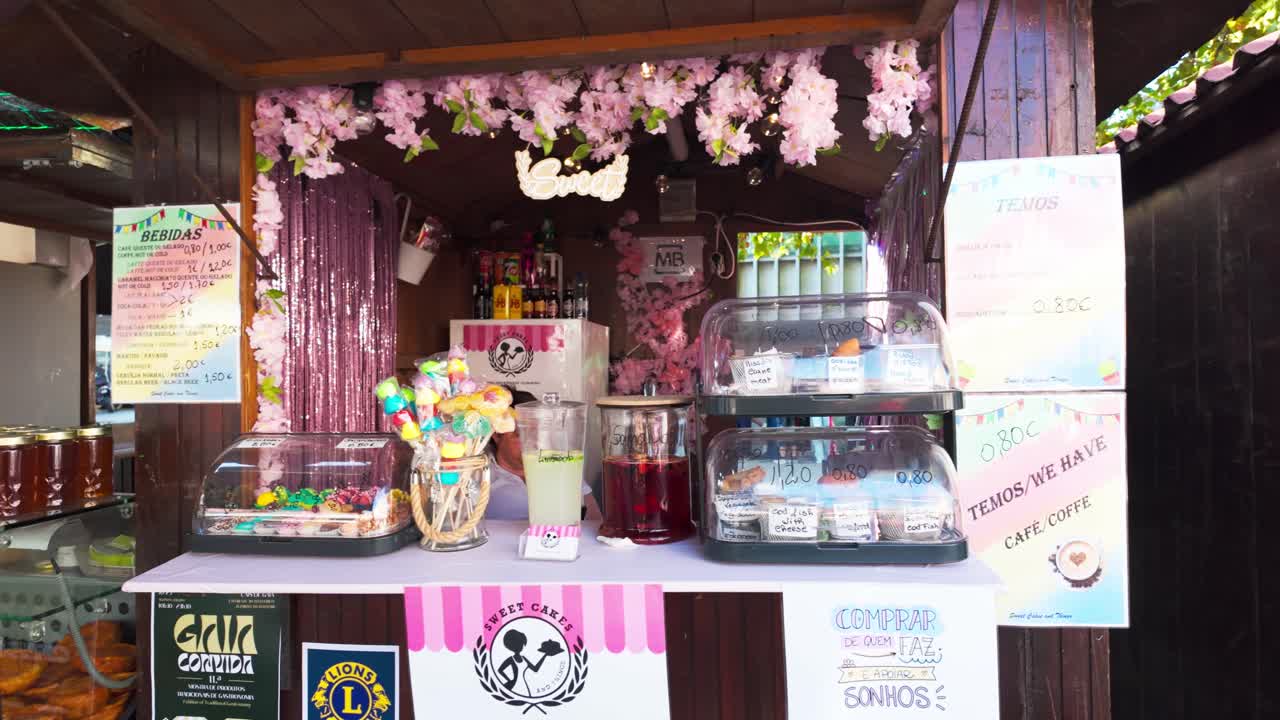 Colorful food stall at Vila Nova de Gaia food market with various sweets, honey, and drinks displayed
