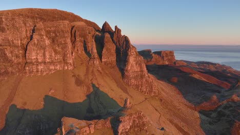 Crumbling-rocky-cliff-spires-of-landslip-bathed-in-dawn-light-with-slow-panning-reveal-of-coastline-and-sea