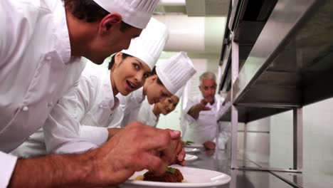 Head-chef-supervising-his-team-garnishing-plates