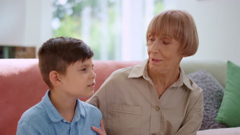 Grandmother-sitting-on-couch-with-grandson.-Senior-woman-and-boy-learning-poetry