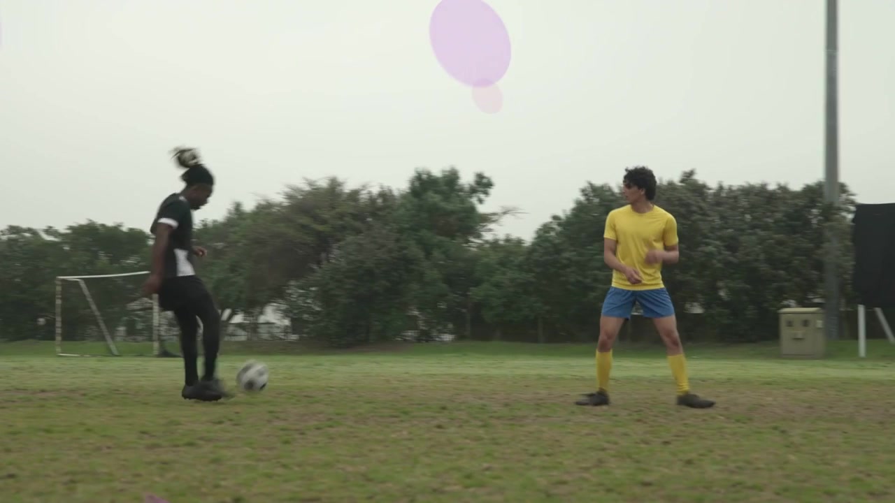 Soccer player in black holding ball near box, dribbling to score while purple rings overlaying net