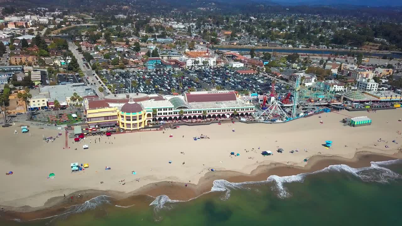 Aerial super wide reverse pull back shot over ocean and revealing full beach boardwalk amusement park.  4K