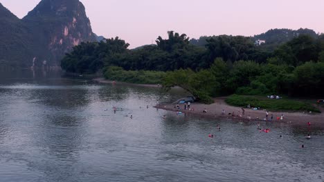 People-bathing-in-river-in-karst-mountain-China-landscape,-aerial-view