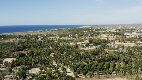 Slow-motion-zoom-In-shot-of-the-Todos-Santos,-the-whole-town-full-of-small-green-bushy-trees,-houses-and-mountain-ranges-on-a-sunny-day-in-Mexico