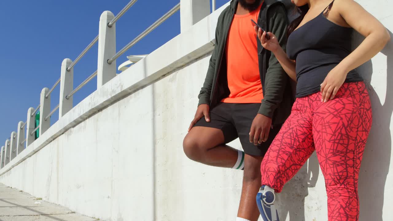 pareja usando teléfono móvil en el paseo marítimo 4k