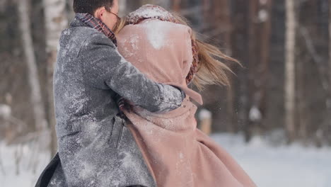 Una-Pareja-Feliz-Está-Jugando-Juegos-De-Invierno-Afuera-Disfrutando-De-La-Luz-Del-Sol-Y-Del-Cálido-Clima-Invernal-En-Las-Montañas.-Un-Chico-Fuerte-Lleva-A-Su-Novia-Sobre-Sus-Hombros-Y-La-Hace-Girar.