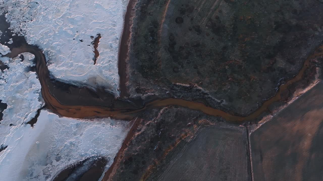 Slow top down aerial zoom, contrast between snow and dark volcanic land Iceland
