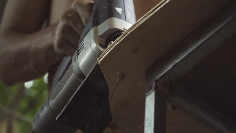 craftsman using an electric jigsaw to shape a skateboard deck from plywood by hand