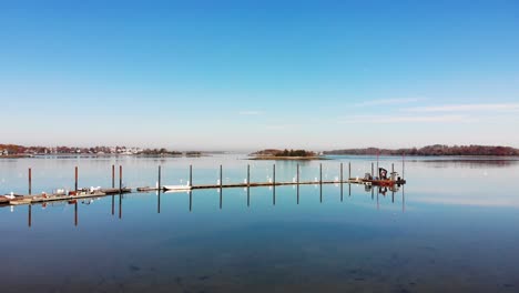 An-Einem-Klaren,-Sonnigen-Tag-Fängt-Eine-Drohne-Eine-Langsame-Annäherung-An-Ein-Dock-Und-Eine-Reihe-Rostiger-Pfähle-In-Einem-Malerischen-Hafen-Ein