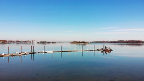 en un día despejado y soleado, un dron captura una progresión lenta hacia un muelle y una serie de pilotes oxidados en un pintoresco puerto