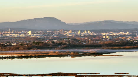 Golden-sunset-over-Montpellier,-highlighting-urban-structures-and-mountain-back