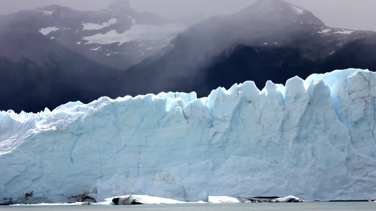 Maestosa parete di ghiacciaio che galleggia nel lago con montagne nebbiose.