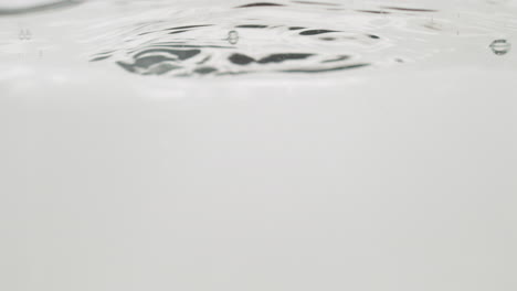 water drops falling on calm surface isolated on pure white color, close up