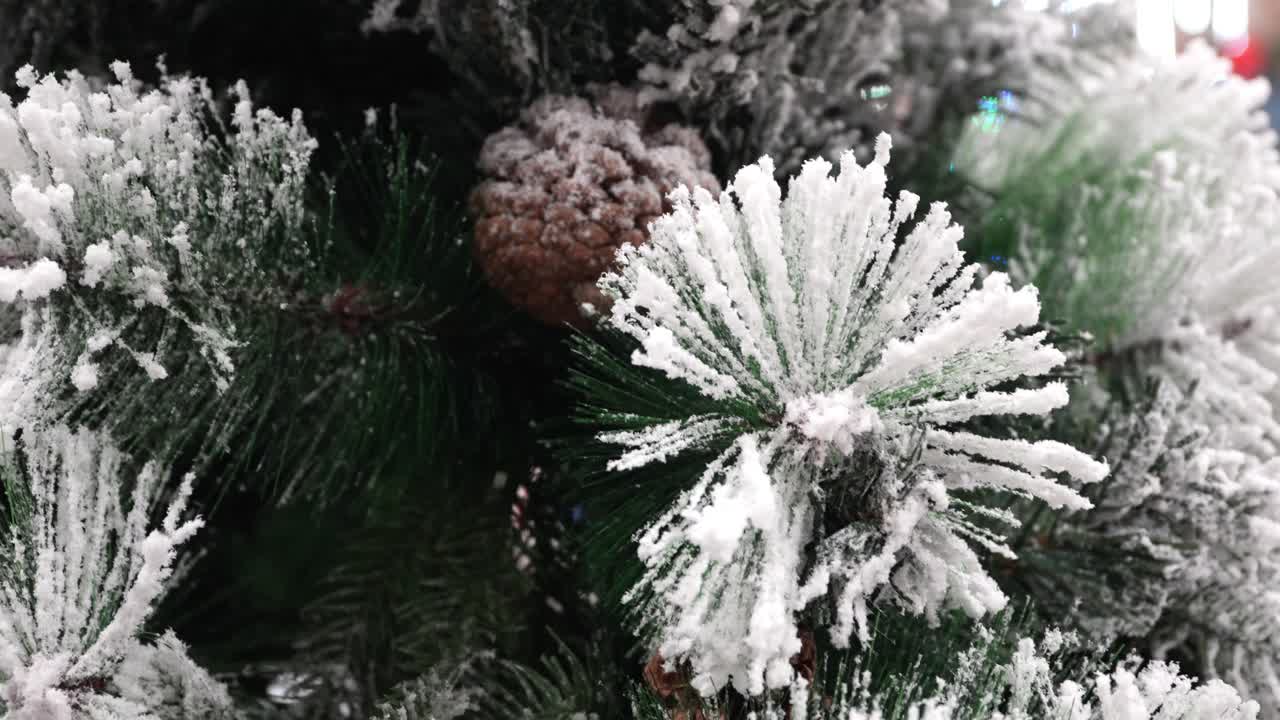 Macro shot of frosted pine needles and a snow covered pine cone on an artificial tree, with soft movement in shallow depth of field