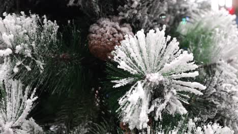 macro shot of frosted pine needles and a snow covered pine cone on an artificial tree, with soft movement in shallow depth of field