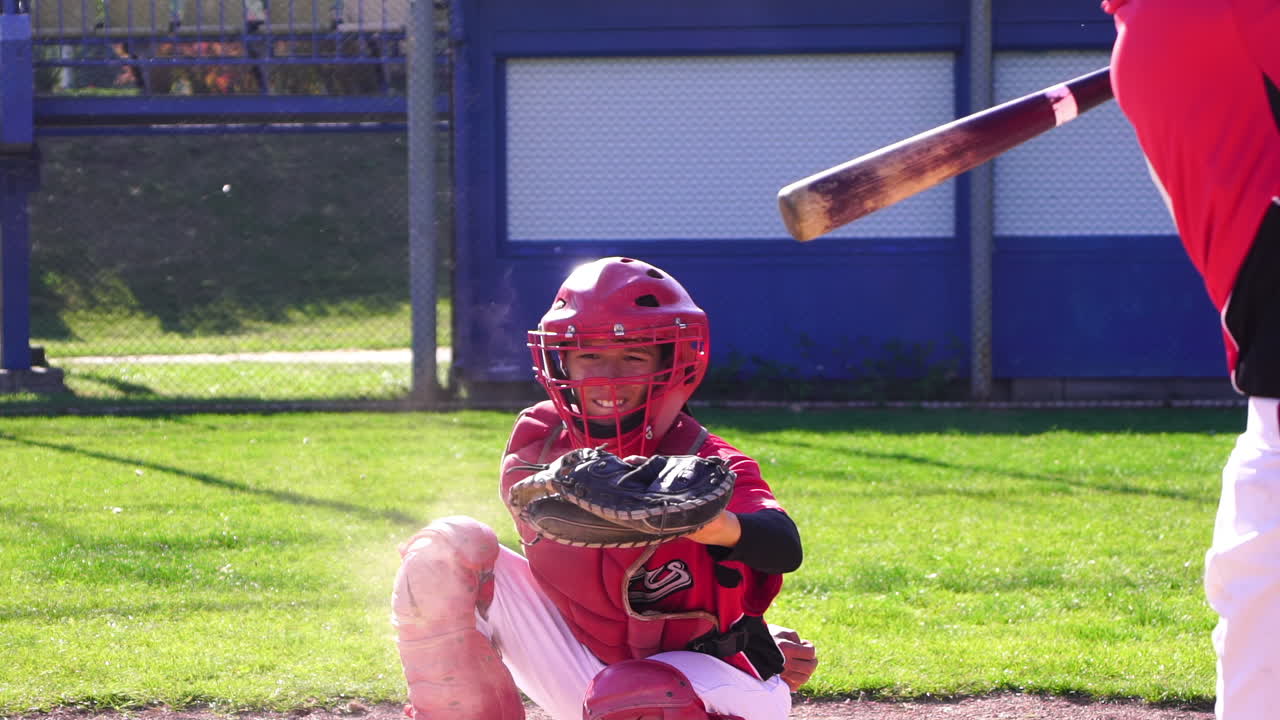 Un giovane ricevitore di baseball è attivamente impegnato in una partita, mostrando abilità e passione.