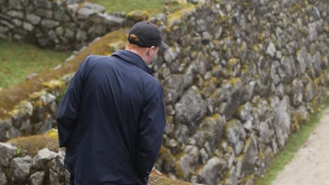 Junger-Kaukasischer-Mann-Erkundet-In-Zeitlupe-Eine-Alte-Verlassene-Indigene-Inka-ruine-Auf-Dem-Inka-pfad-In-Den-Anden-In-Peru