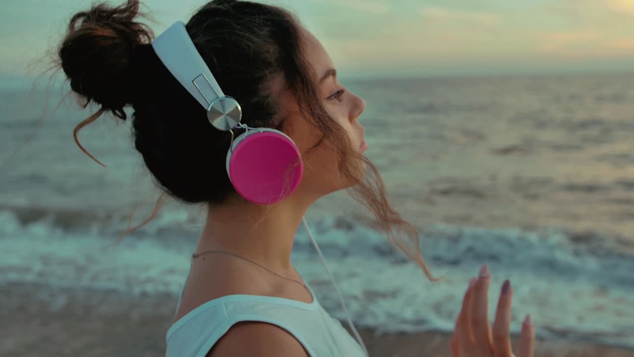 una adolescente con auriculares caminando por la playa. filmada a cámara lenta