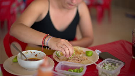 Cierre-En-Cámara-Lenta-De-Una-Mujer-Latina-Mordiendo-Un-Taco-De-Barbacoa-Con-Salsa-De-Chile-Verde-En-Un-Restaurante-En-México