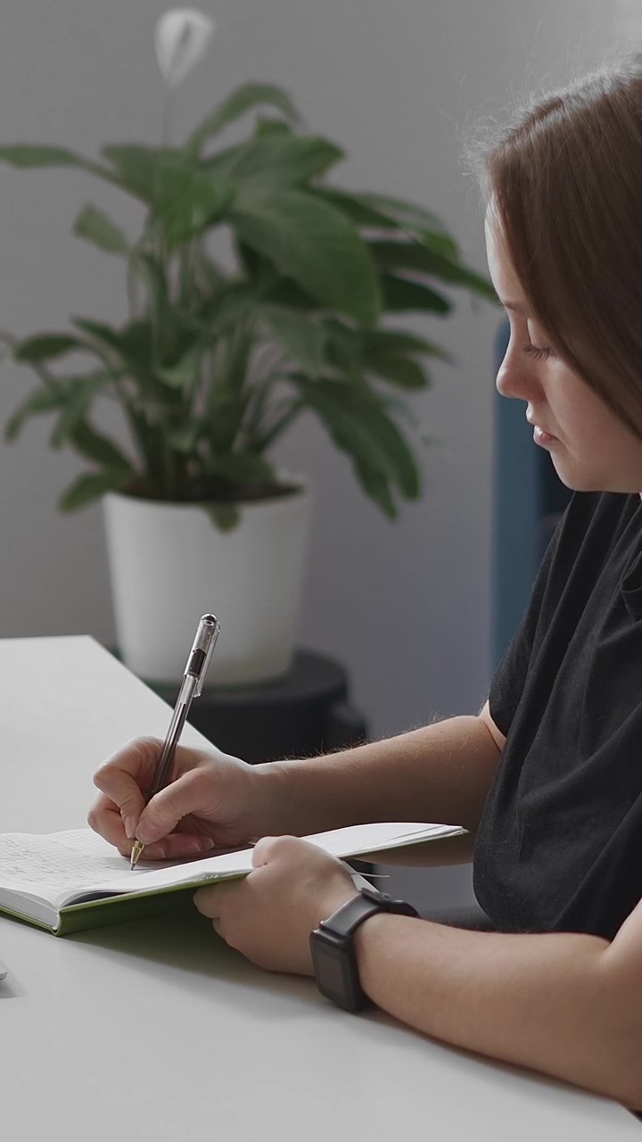 Young Woman Writing in a Notebook at a Desk