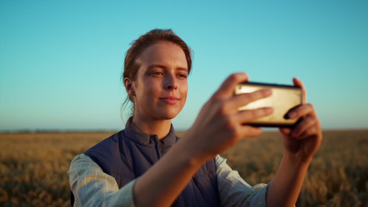 mujer tomando una foto de campo en golden farmland view. retrato de un trabajador agrícola.