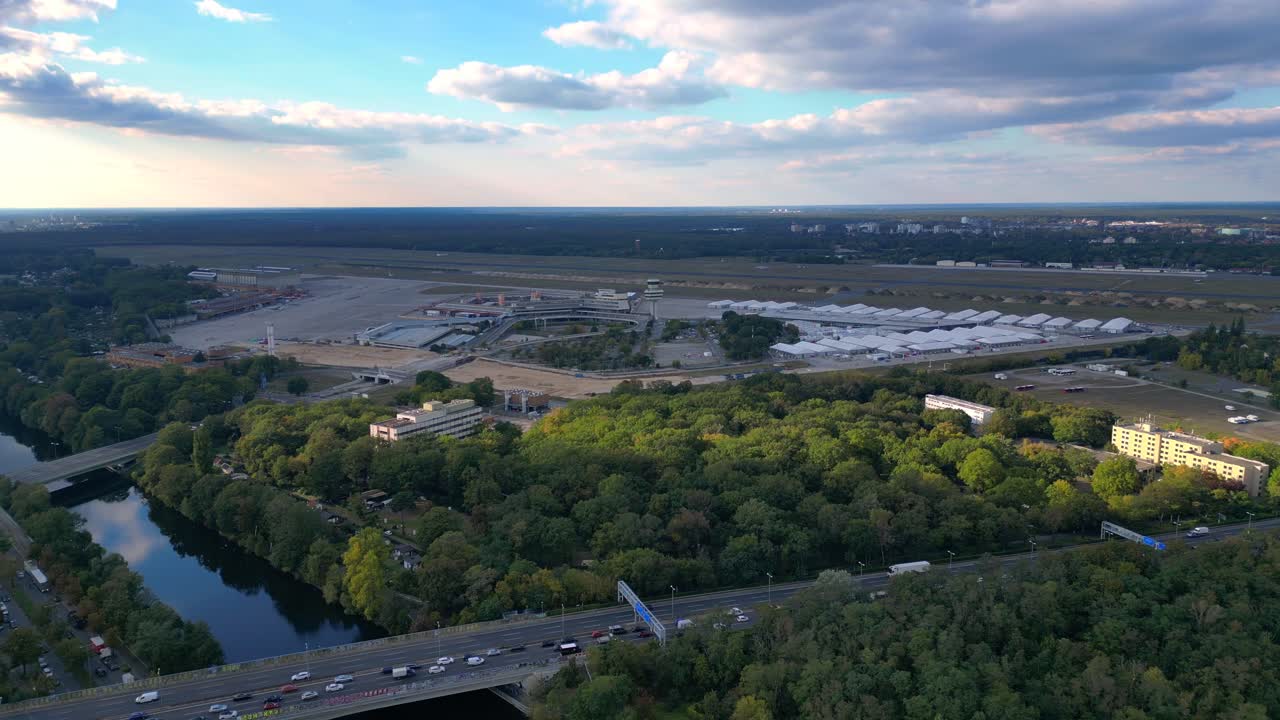 Berlin Tegel Airport, a busy highway, and a connecting river winding through green trees. Stunning aerial view flight static tripod hovering drone