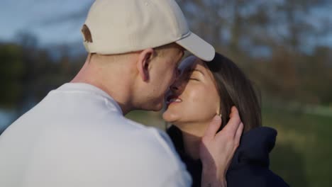 una pareja encantadora en el parque, un chico toca suavemente la mejilla y besa a su novia en los labios.