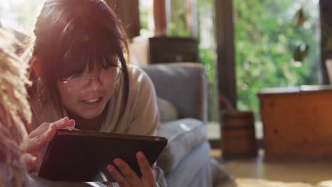 Asian-girl-lying-on-couch-and-using-tablet-smiling