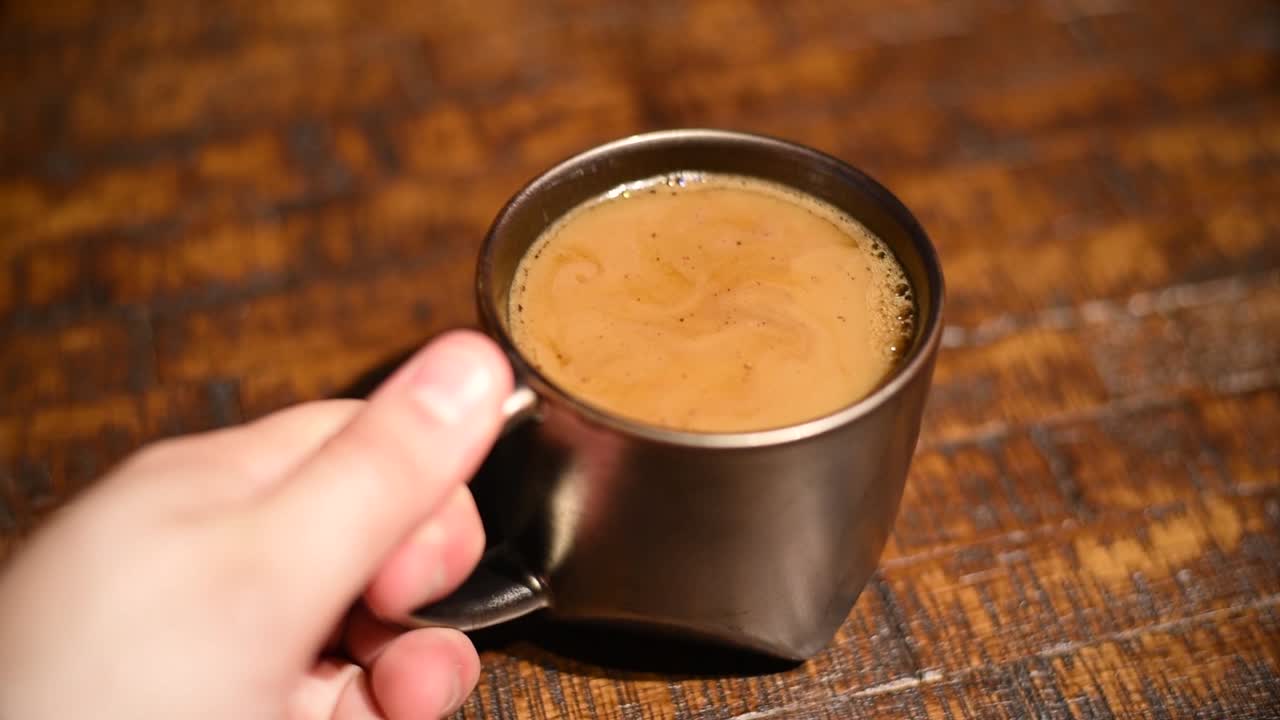 Hand grabbing a mug with coffee in it to drink.